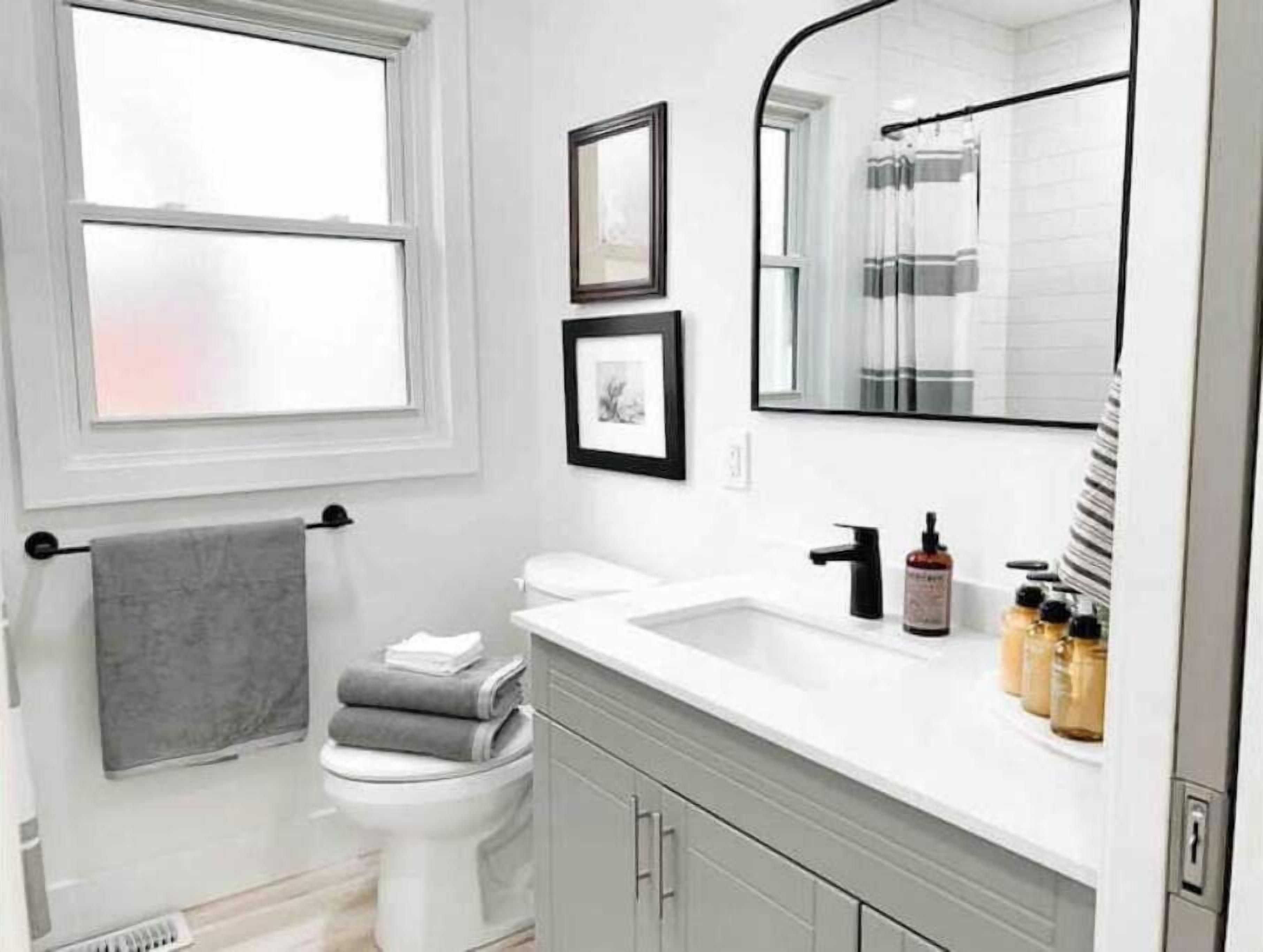 Een moderne badkamer met een wit wastafelmeubel, toilet en raam.