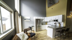 Eine moderne Küche mit weißen Schränken, einem Edelstahlkühlschrank und einer eingebauten Mikrowelle.