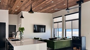 A modern kitchen with a large island, a green sofa, and a fireplace. - Modern 3 bedroom home on 20 private acres in Paradise Valley (Livingston)