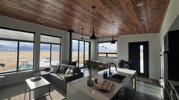 A modern kitchen with a large island, a dining area with a view of mountains, and a cozy seating area with a view of a snowy landscape. - Modern 3 bedroom home on 20 private acres in Paradise Valley (Livingston)