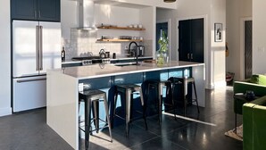 A modern kitchen with a central island, bar stools, and stainless steel appliances. - Modern 3 bedroom home on 20 private acres in Paradise Valley (Livingston)