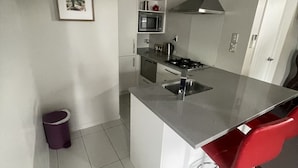 Una cocina moderna con una isla central, electrodomésticos de acero inoxidable y una silla roja.
