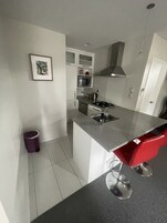 Uma cozinha moderna com ilha central, eletrodomésticos de aço inoxidável e uma cadeira vermelha.
