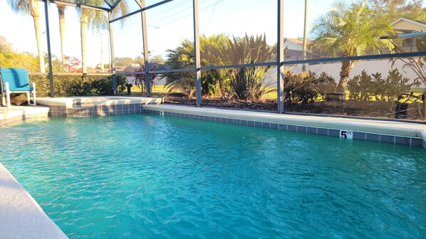 A swimming pool with clear blue water, a 3ft and 5ft depth marking, and a covered area with a blue chair. - New to rentals, South Facing pool and spa, free WiFi, smart TV's, 2 Master suites (Haines City)