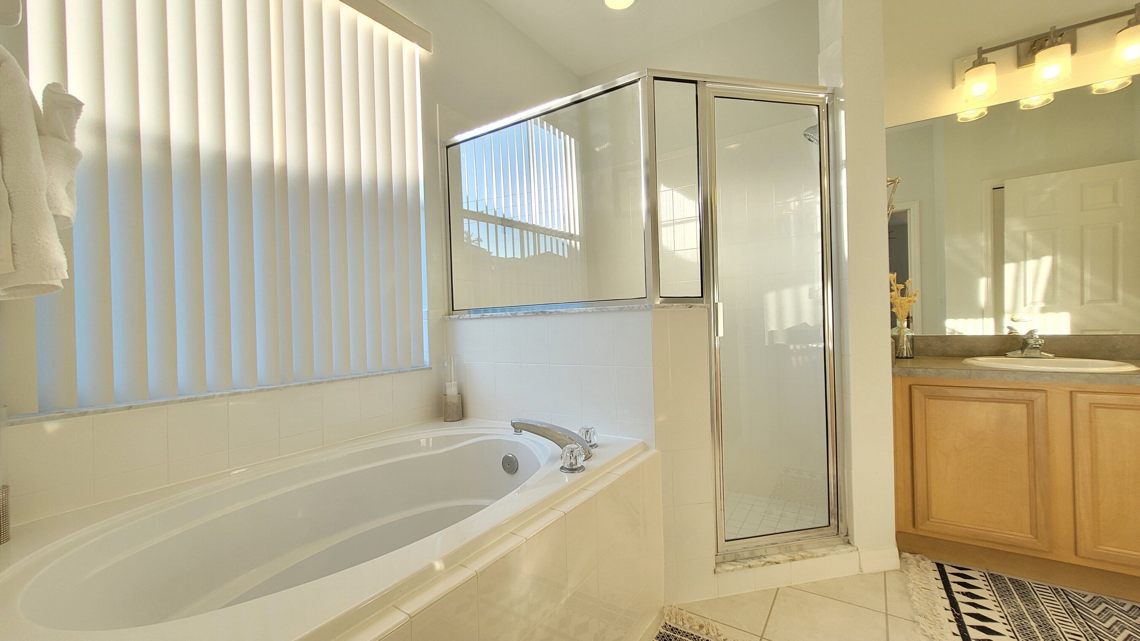 A modern bathroom with a bathtub, a glass-enclosed shower, and a vanity with a sink.
