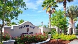 A sign for Calabay Parc at Tower Lake with a landscaped garden and palm trees. - New to rentals, South Facing pool and spa, free WiFi, smart TV's, 2 Master suites (Haines City)