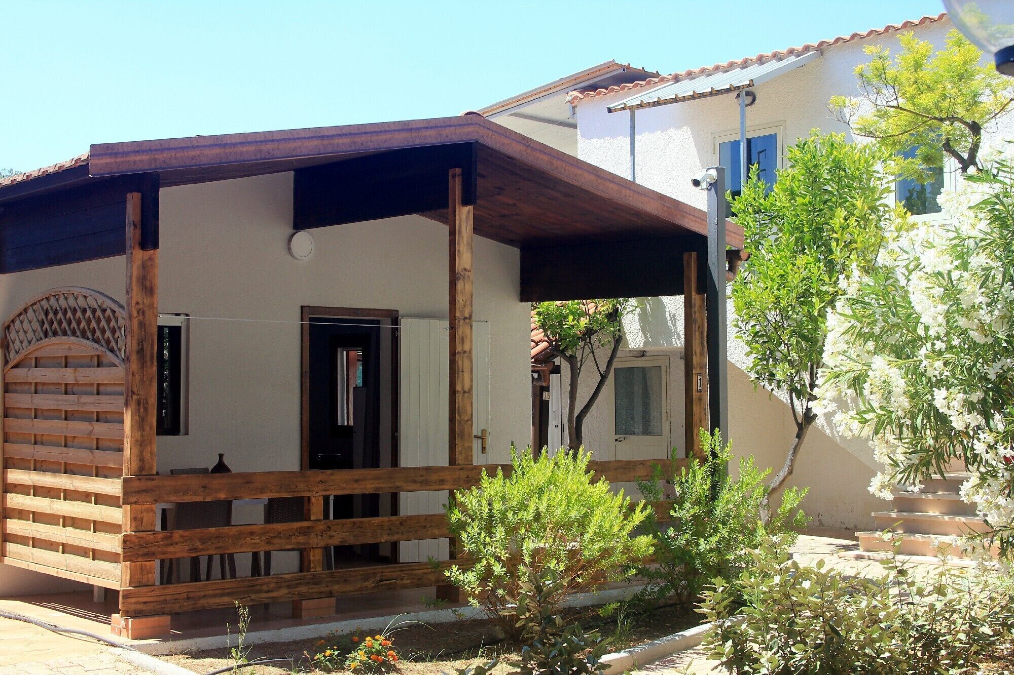 Un edificio tradizionale con un portico in legno, una porta e un piccolo giardino fiorito.