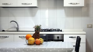 A kitchen with white cabinets, a stainless steel range hood, a gas stove, and a sink.