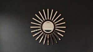 Een bed met gestreepte lakens, twee kussens en een zonnespiegel aan de muur.