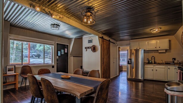 Una cocina moderna con electrodomésticos de acero inoxidable, una mesa de comedor de madera y vistas al exterior.