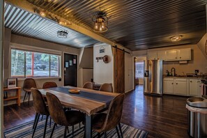 A modern kitchen with stainless steel appliances, a wooden dining table, and a view of the outdoors. - Cozy cottage nestled in the middle of Cloudcroft (Cloudcroft)