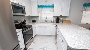 A kitchen with white cabinets, a stainless steel microwave, a built-in oven, and a granite countertop.