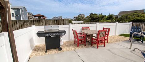 A backyard with a barbecue grill, a pool, and a table with chairs.