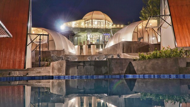 Un bâtiment moderne doté d’un grand dôme et d’une piscine en premier plan.