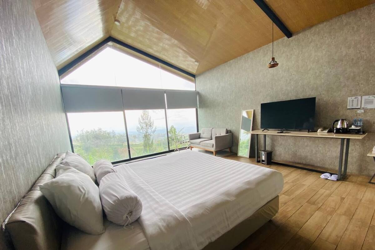 A bedroom with a large bed, a TV, and a desk.