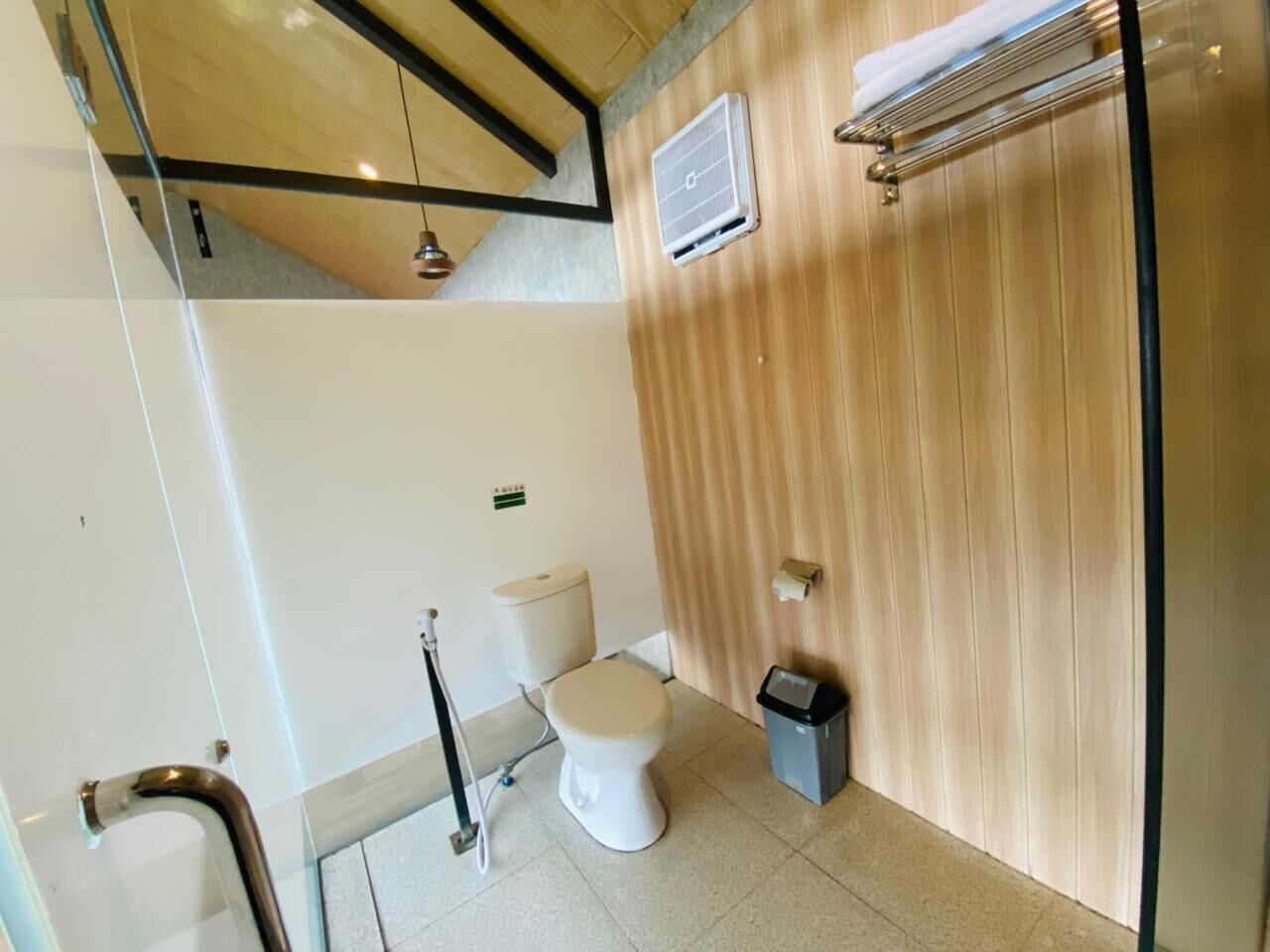 Ein modernes Badezimmer mit Toilette, Mülleimer, Handtuchhalter und Handlauf.