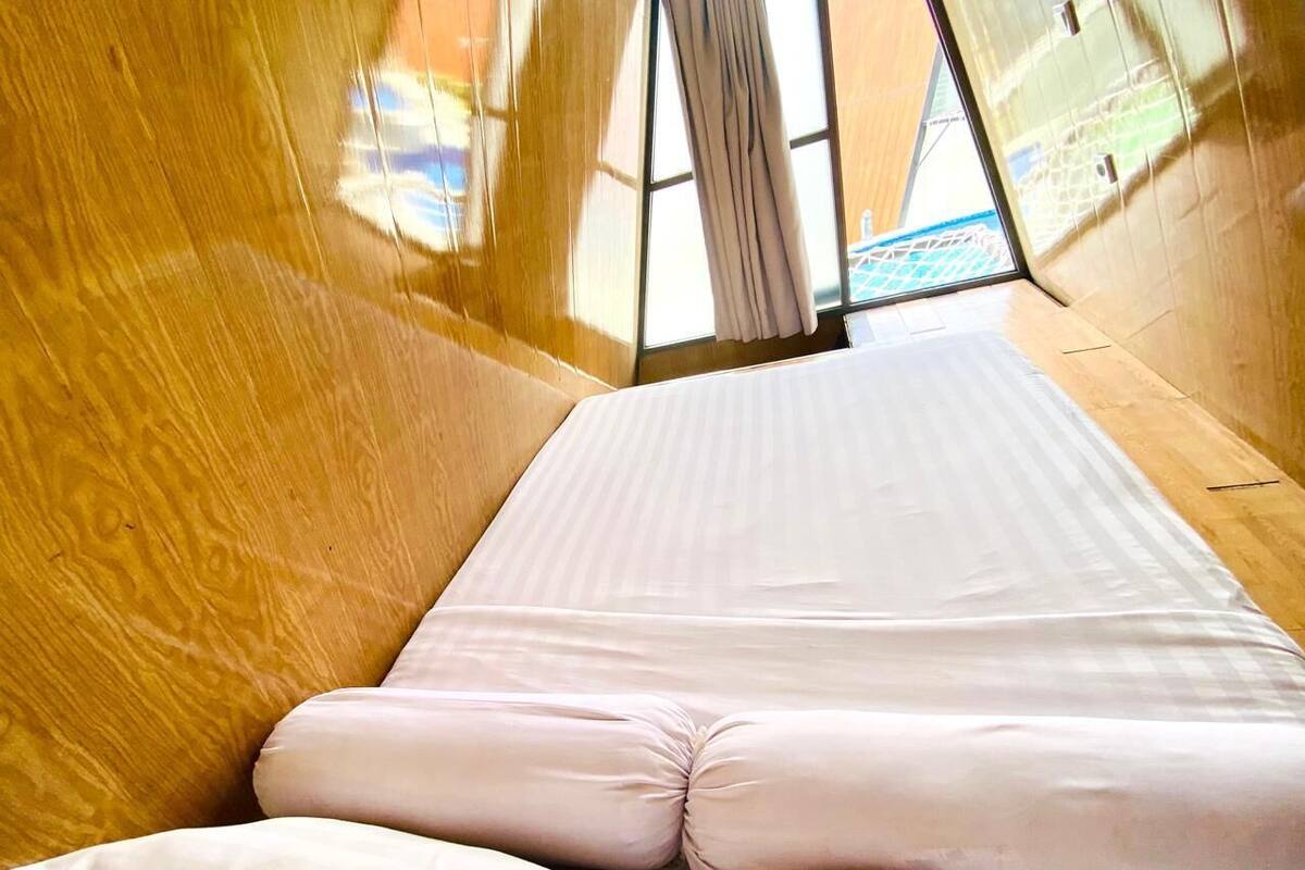 A room with a bed, wooden walls, and a view through a window.