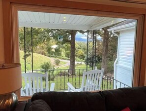 A room with a view of a garden through a window. There are two white chairs outside the window. - Blue Ridge Mountain Cottage close to everything Asheville has to offer.  (Asheville)