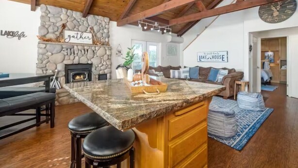 Una cocina amplia con pared de piedra, vigas de madera, encimera de granito y chimenea.