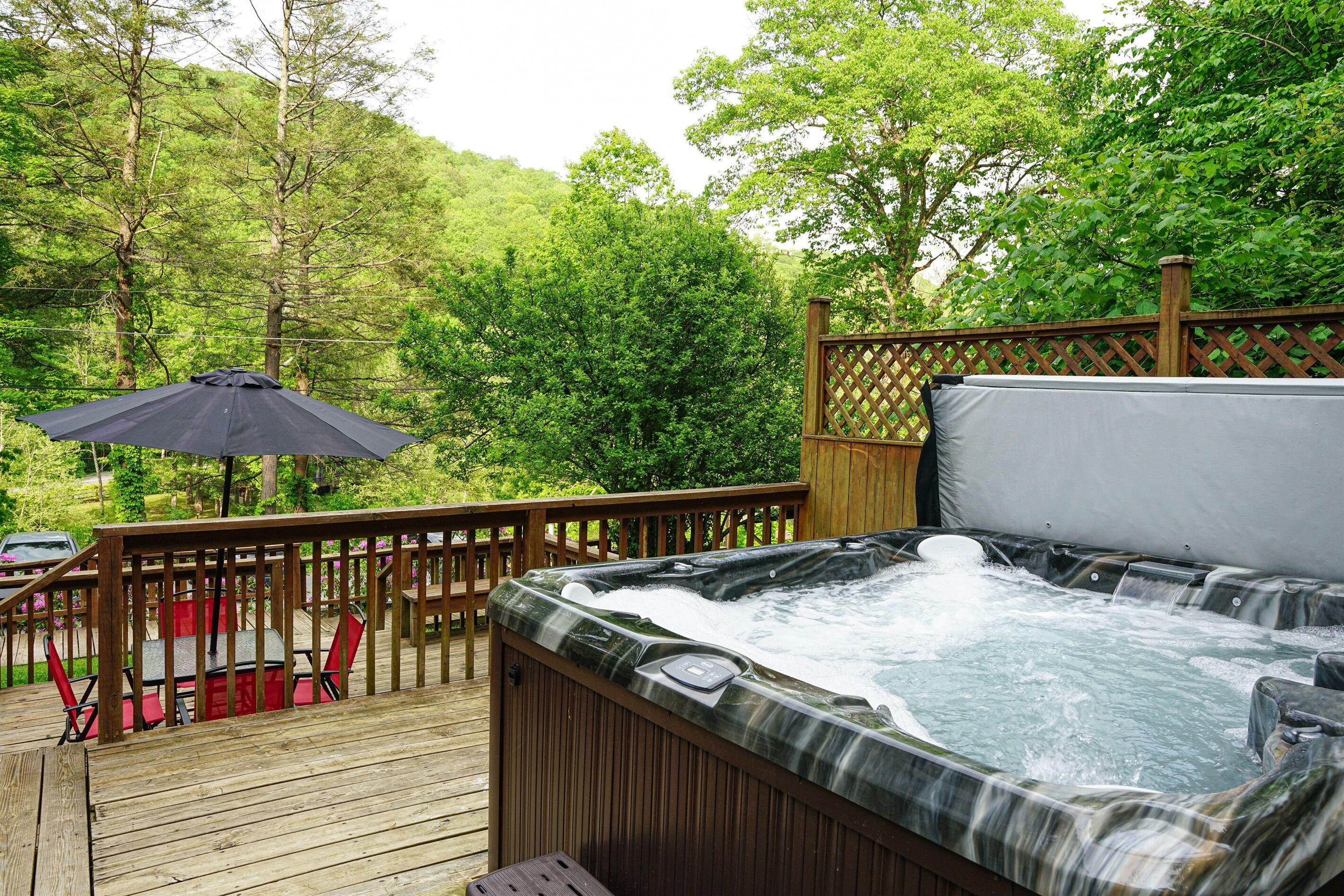 A hot tub on a wooden deck with a wooden fence and chairs.