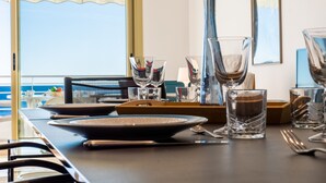 A dining table set with various glassware and a laptop, overlooking a scenic view. - PANORAMIC SEA VIEW - 2-Br Apartment Mouré Rouge (Cannes)