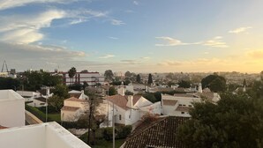 Un quartier résidentiel avec des bâtiments blancs, dont certains ont des toits rouges, et un ciel dégagé parsemé de nuages.