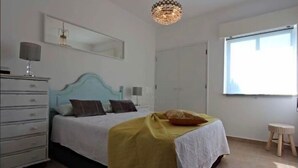 Une chambre à coucher avec un lit, une commode, un miroir et une fenêtre.
