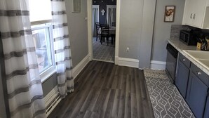 A modern kitchen with grey cabinets, a microwave, and a dishwasher. There is a dining area with a table and chairs visible through an open door. - Cozy Little Getaway, Winner, SD (Winner)
