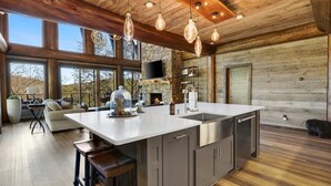 A spacious kitchen with a large island, wooden ceiling, and large windows offering views of the outdoors. - Top 10 VRBO in U.S. Riverfront, Hot Tub, Sleeps 12, As seen on TV! (Epworth)