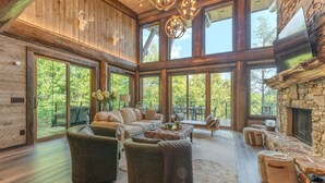 A spacious living room with a large sofa, ottomans, and a stone fireplace. - Top 10 VRBO in U.S. Riverfront, Hot Tub, Sleeps 12, As seen on TV! (Epworth)