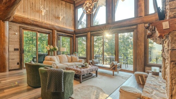 A spacious living room with a large sofa, two armchairs, a coffee table, and a fireplace. - Top 10 VRBO in U.S. Riverfront, Hot Tub, Sleeps 12, As seen on TV! (Epworth)