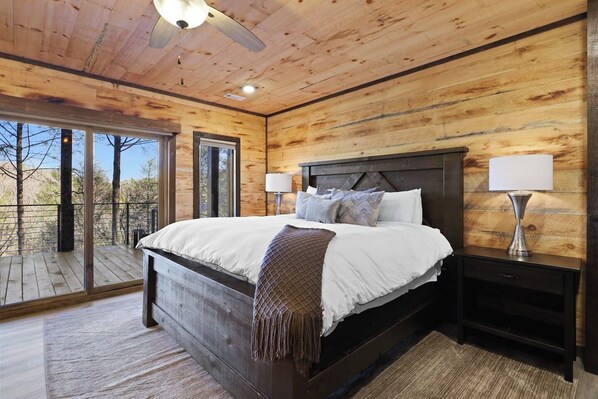A wooden-paneled bedroom with a bed, nightstands, and a ceiling fan.