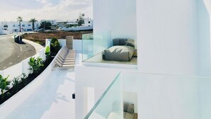 A modern, white building with a glass balcony overlooking a road and a beach. - CIH Apartments (Puerta del Carmen)