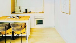 A modern kitchen with a wooden table and chairs, a built-in oven, and a hanging light fixture. - CIH Apartments (Puerta del Carmen)
