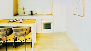 A modern kitchen with a wooden dining table and chairs, a built-in oven, and a hanging light fixture. - CIH Apartments (Puerto del Carmen)