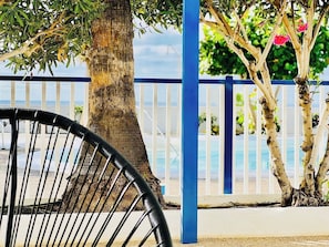 Une vue sur la plage avec une chaise, un arbre et une clôture bleue.