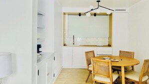 A modern kitchen with white cabinets, a wooden dining table with six chairs, and a pendant light above the counter. - CIH Apartments (Puerto del Carmen)