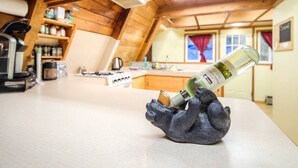 A kitchen with wooden beams, a countertop, and a bottle of wine on a decorative holder.