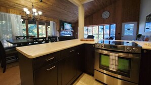 Una cucina moderna con mobili scuri, un forno in acciaio inossidabile e una grande isola con piano di lavoro.
