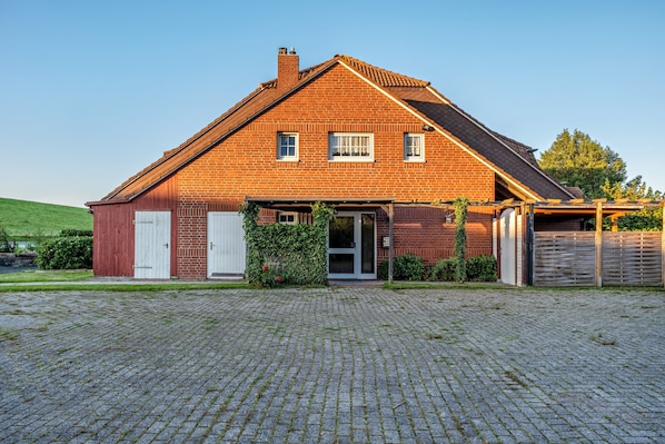 A brick house with a sloped roof, a garage, and a paved driveway.