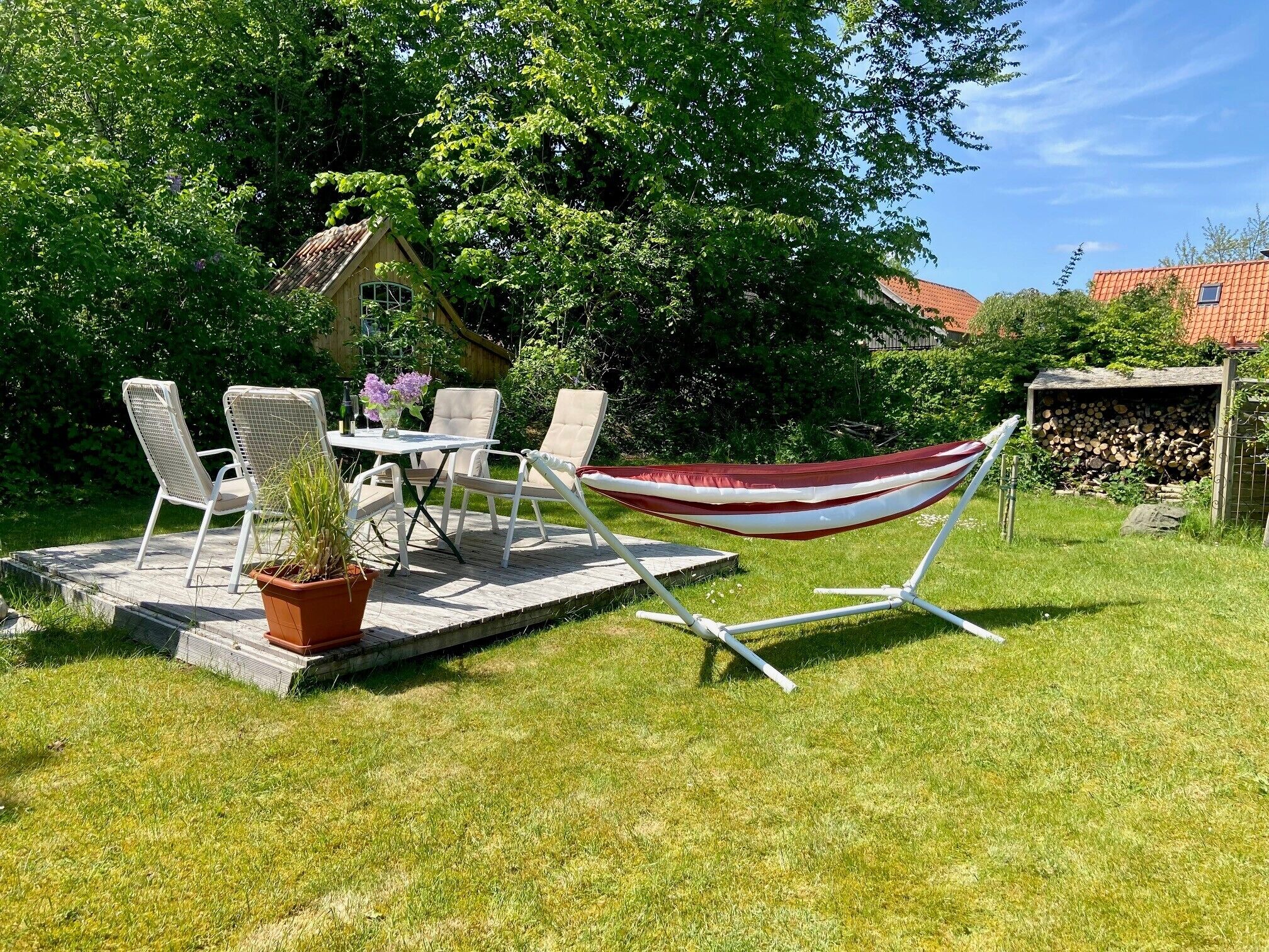 Eine Terrasse mit Tisch, Stühlen, einer Hängematte und einem Blumentopf.