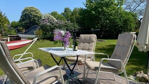 An outdoor deck with a table and chairs, surrounded by greenery and trees.