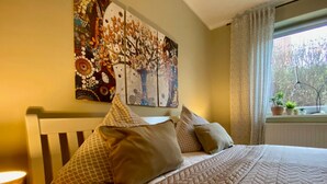 A bed with a quilted cover, pillows, and a wall art piece above it.