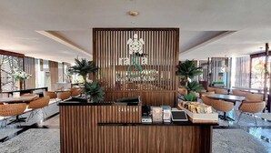 A reception area with a wooden counter, wicker chairs, and a decorative wall. - Sekuro Village Beach Resort (Mlonggo)