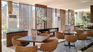 A hotel dining area with wicker chairs and tables, a decorative wall, and a view of the outdoors. - Sekuro Village Beach Resort (Mlonggo)