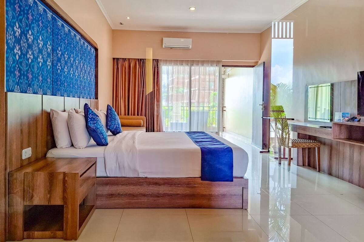 A modern hotel room with a large bed, a wooden nightstand, a desk, and a TV.