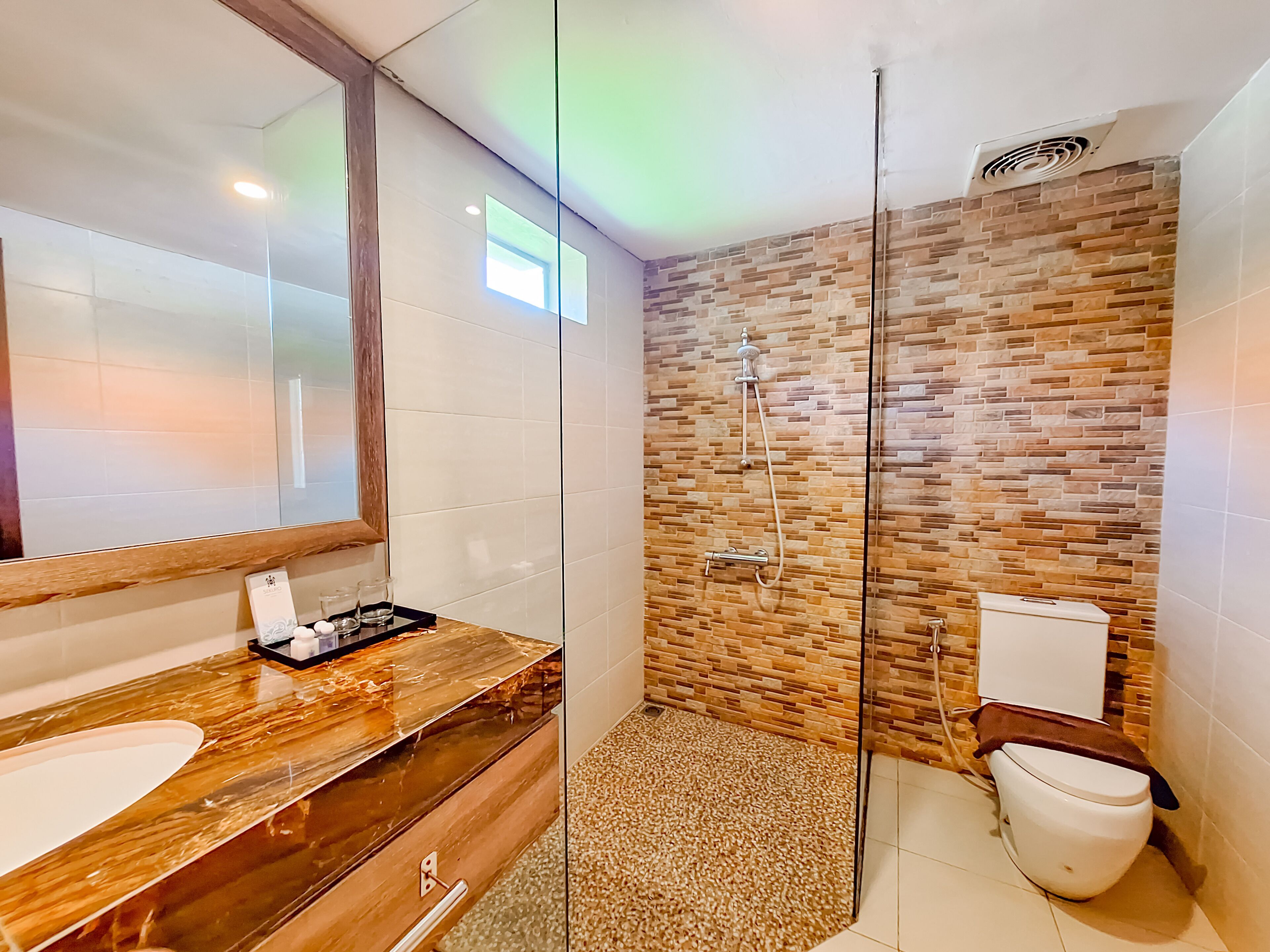 A modern bathroom with a glass-enclosed shower, a wooden vanity, and a large mirror.