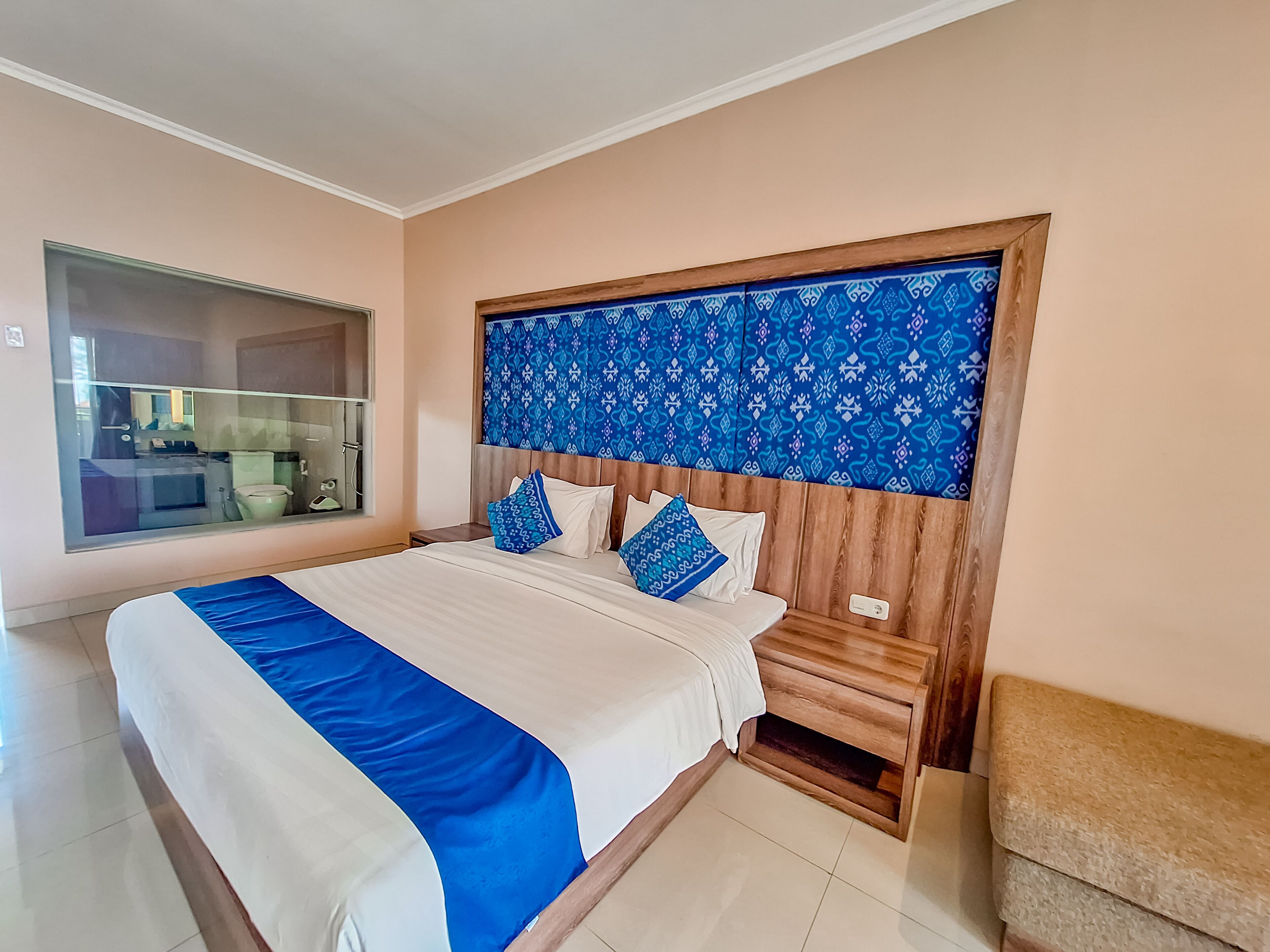 A bedroom with a large bed, wooden headboard, and a mirror above the bed.