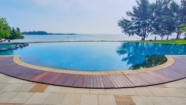 A pool with a wooden deck and a view of the sea. - Sekuro Village Beach Resort (Mlonggo)