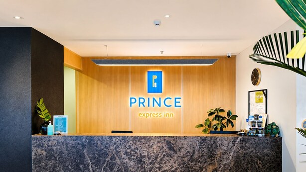A hotel reception desk with a marble counter, a wooden panel wall, and a sign that reads 'PRINCE express inn'.